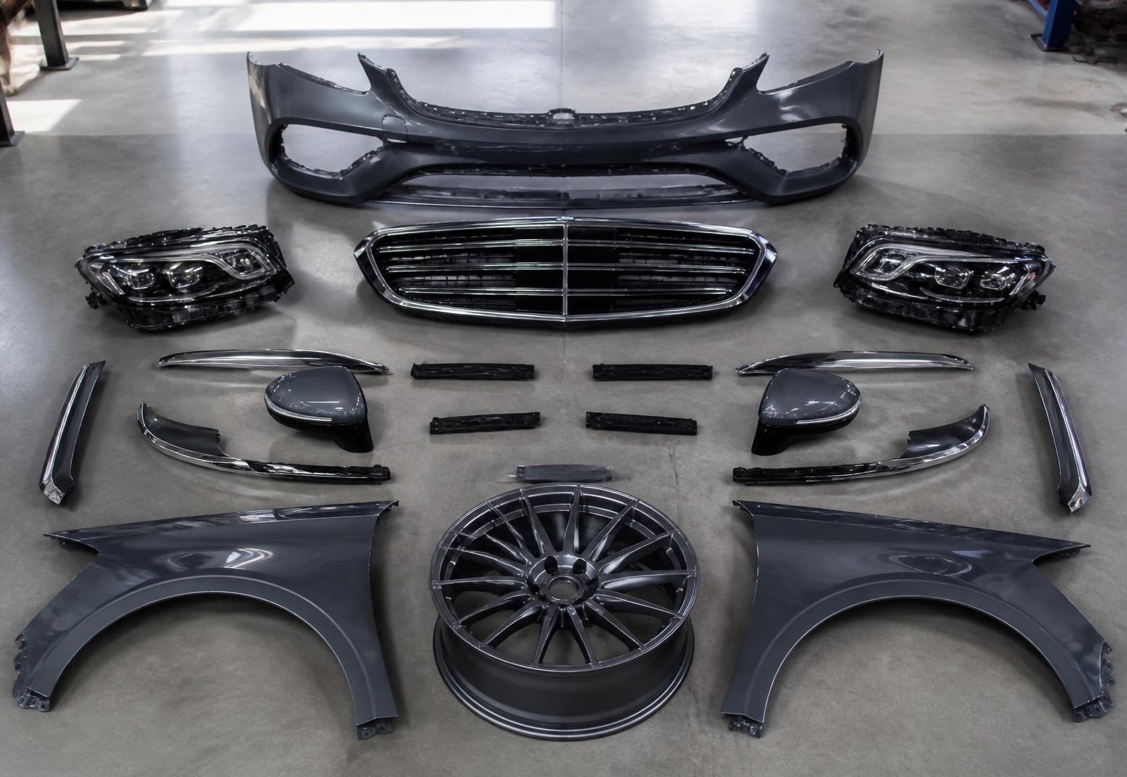 Mercedes-Benz front bumper, chrome grille, LED headlights, mirror caps, fenders and a forged wheel laid out for inspection